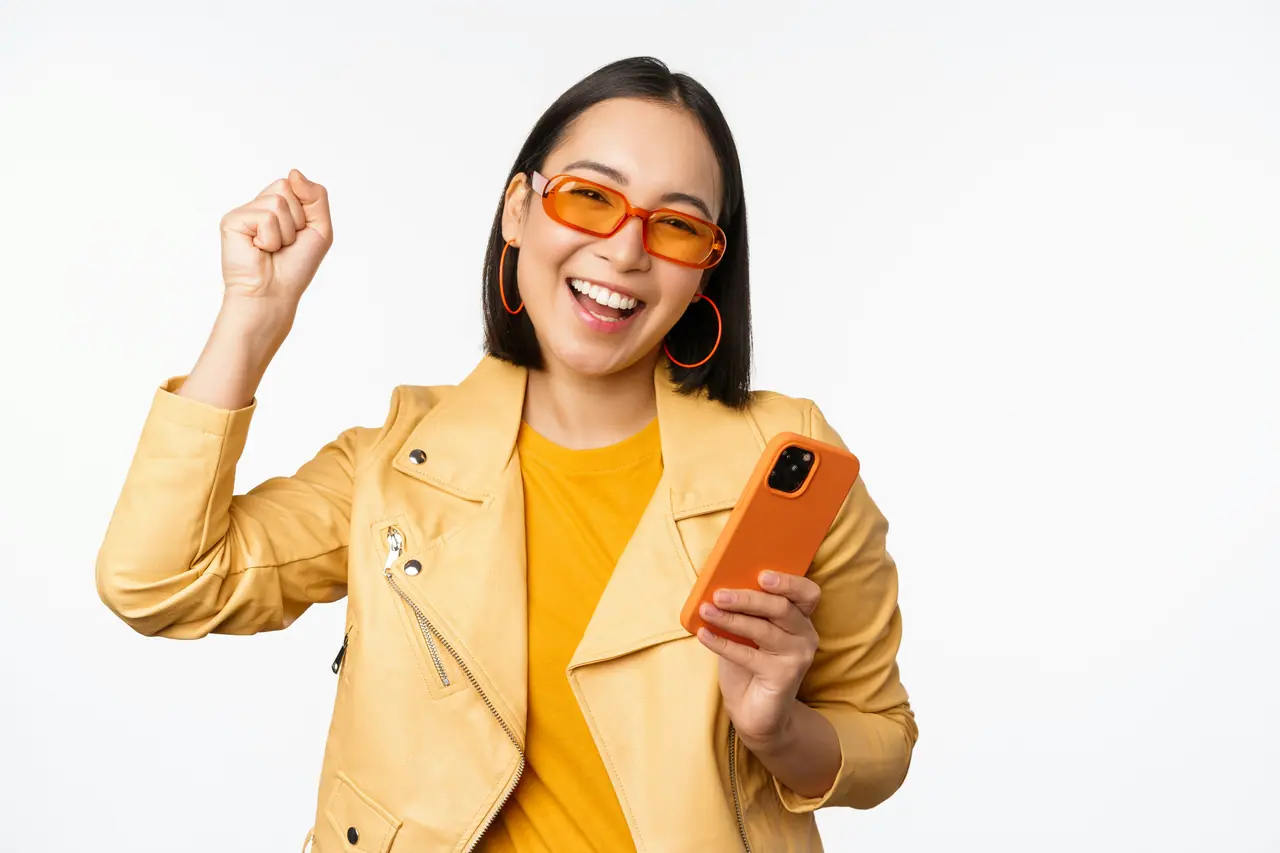 Mulher comemorando com o celular na mão
